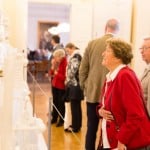Ausstellungsbesucher betrachten Taufkleider-Galerie. Foto: Schlossmuseum/Marek Kruszewski