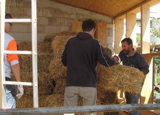 Dr. Bernd Hoppe-Dominik (rechts) und seine Mitstreiter bauen die ersten Strohballen in die Holzständer ein. Foto: FUN