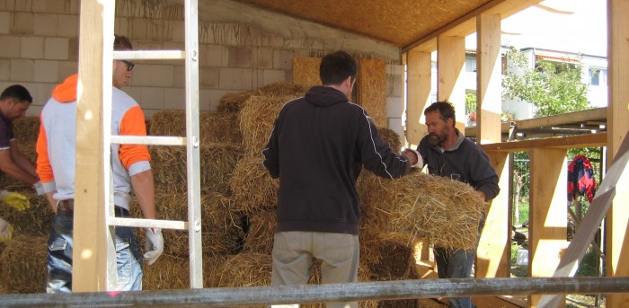 Dr. Bernd Hoppe-Dominik (rechts) und seine Mitstreiter bauen die ersten Strohballen in die Holzständer ein. Foto: FUN