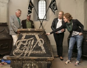 Textilrestauratorin Sabine Kießler zeigt Erika Borek und Hans Kolmsee (links) sowie Thomas Musahl vom Herzoglich Braunschweigischen Feldcorps Details am restaurierten Sarg. Die Frontseite zeigt die Initialen „FW“. Foto: Peter Sierigk