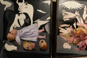 Hommage an Picasso und sein Gemälde Guernica: Zerstörte Puppen vor dem Historienbild.