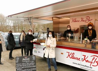 Tobias Henkel (Stiftung SBK, Vierter von links) und Rotkreuz-Präsidiumsmitglied Gabriele Heinen-Kljajic (Bildmitte) haben ihren Imbiss vorm neuen Food-Truck „Kleinen Kaufbar“ in Empfang genommen. Links Heike Blümel, Antje Kämpfe und Reem Alshaer sowie von rechts Estelle Nabou Münzel und Valeria Paim vom DRK. Foto: Karsten Mentasti / DRK