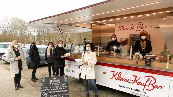 Tobias Henkel (Stiftung SBK, Vierter von links) und Rotkreuz-Präsidiumsmitglied Gabriele Heinen-Kljajic (Bildmitte) haben ihren Imbiss vorm neuen Food-Truck „Kleinen Kaufbar“ in Empfang genommen. Links Heike Blümel, Antje Kämpfe und Reem Alshaer sowie von rechts Estelle Nabou Münzel und Valeria Paim vom DRK. Foto: Karsten Mentasti / DRK