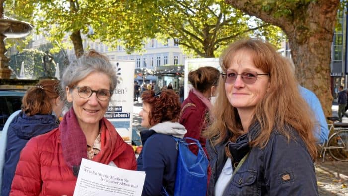 Petra Scholz-Marxen (links), Geschäftsführerin und Koordinatorin des Vereins Hospizarbeit Braunschweig, unterhält sich am Infostand auf dem Kohlmarkt mit ihrem Gast Katrin Sopper, im Hintergrund ist die ehrenamtliche Mitarbeiterin Ann-Kathrin Lumpe ebenfalls in Gesprächen. Foto: Bernward Comes