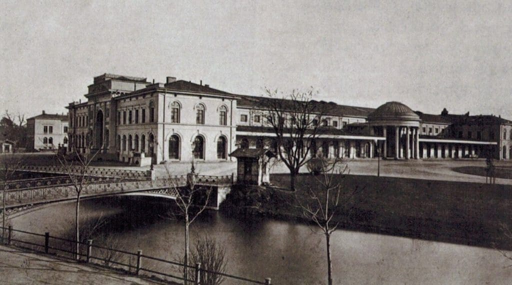Blick vom Friedrich-Wilhelm-Platz zum alten Hauptbahnhof mit Eingangsrotunde und Eisenbrücke über den Umflutgraben, um 1880. Foto: Stadtarchiv