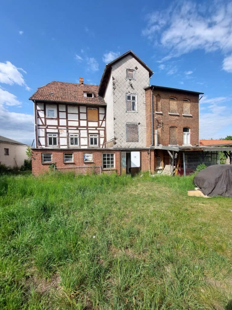 Alt: Historisches verfallenes Haus mit Fachwerk und Ziegelarchitektur unter blauem Himmel.